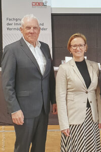 Mann im Anzug, Frau in Kleid, nebeneinander stehend