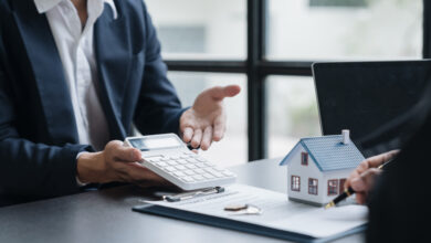 Hand einer Frau, die auf einen Taschenrechner und einen Vertrag zeigt