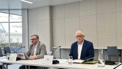 Zwei Herren bei einer Pressekonferenz, vor ihren Mikrophonen